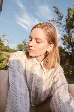 portrait of a blonde girl in a white shirt on nature in the rays of light