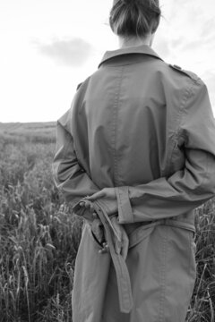 black and white photo of a girl in a raincoat with her back to the camera with hands behind her back