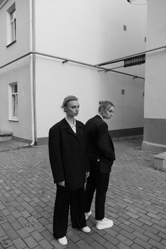 black and white photo of two young beautiful sisters on the streets of the city while walking in strict dark suits