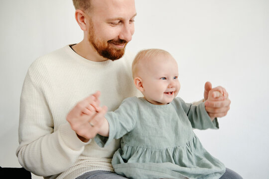 portrait of a happily smiling dad holding the hands of a laughing little daughter