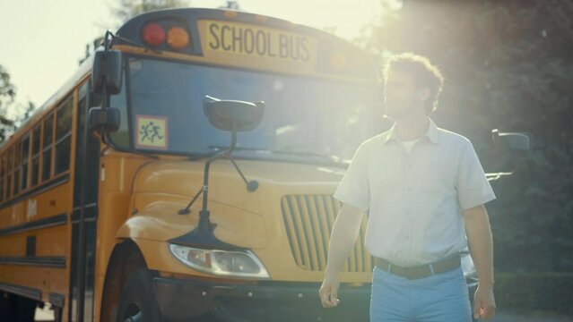 Young schoolbus driver stand near academic shuttle alone. Chauffeur man posing.