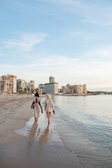 Naklejka premium Women walking on beach towards hotels