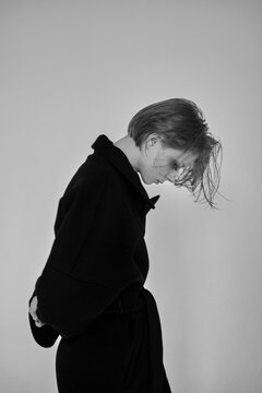 black and white art portrait of a girl in profile in a long black coat on a light background