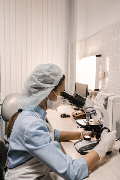 Nurse using a microscope examines blood cells