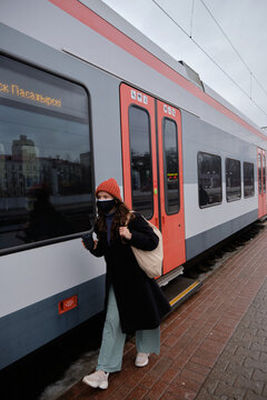 a girl in stylish clothes with a bag on her shoulder at the station walks along the train vogue