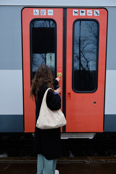 girl in stylish clothes with a bag on her shoulder at the station in front of the train