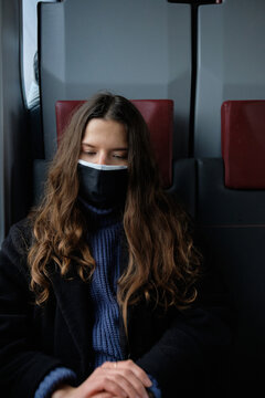 a lonely girl in a train wearing a mask sits on a chair in a train near the window
