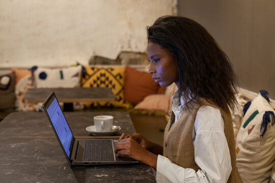female entrepreneur working with digital documents on laptop in cafe