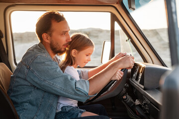 Father and daughter driving car in desert