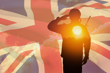 Silhouette of soldier with print of sunset saluting on a background of United Kingdom flag....