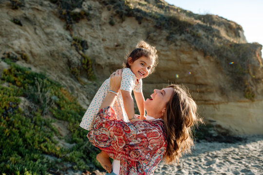 Mom lifts happy daughter in the air