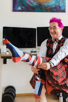 Happy man with pink hair putting the checkered socks on