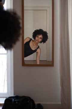 Stunning African woman at home looking at herself in the mirror
