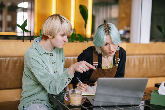 Woman rewriting information from laptop in copybook 