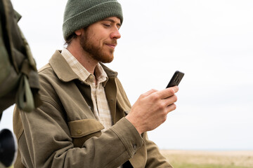 Fototapeta premium Portrait of young man using phone outdoors in winter