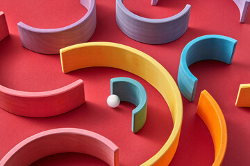 Arched wooden planks and ball lying on red background