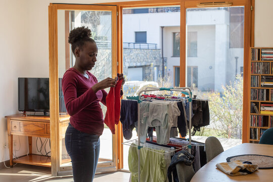 Laundry, Woman Folding Baby Clothes From Dryer At Home