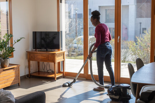 woman hoovering floor at home using vacuum cleaner