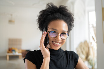 A woman with glasses, a freelancer working in an office, is using the phone and smiling