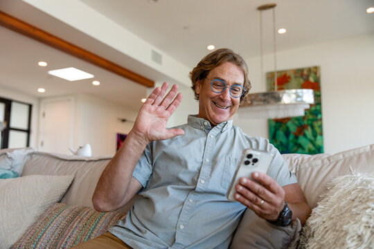 Older Man Waves While On His Phone