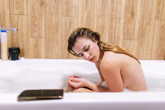 Sensual woman with nacked body and wet hair relaxing in foam water