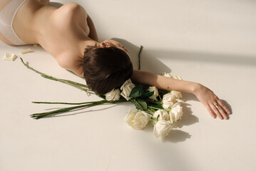 A girl lays down on the floor in the underwear with white roses