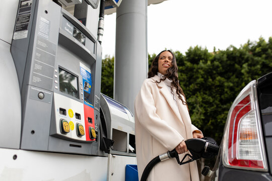 Fashionable Woman Grimaces While Filling Up Her Gas Tank