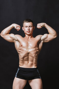 Bodybuilder man showing biceps and abs muscles on black background