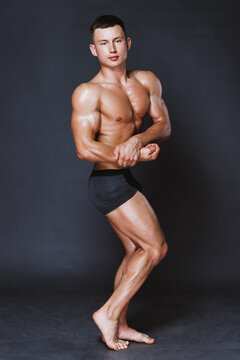 Athletic male in swimming trunks tensing body while turning to camera