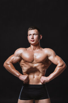 Muscular male model with strong body posing on black background