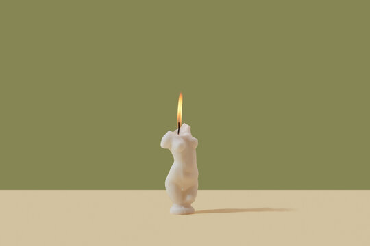 Lit candle in shape of faceless woman body