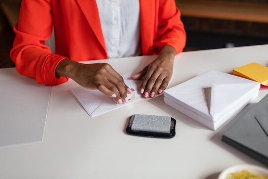 Cropped female stamping envelope invitations