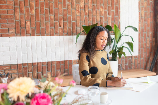 Beautiful young executive taking notes at work