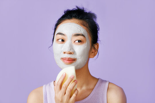 Beautiful woman removing gray-blue mask from her face