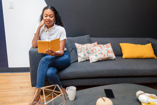 Woman in break time reading digital book on sofa at work