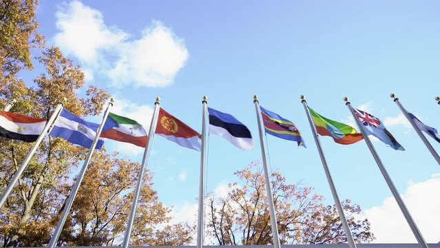 Flags flying in wind in front of United Nations in NYC. Estonia, Eswatini, Ethiopia, Eritrea flags. Sky in background