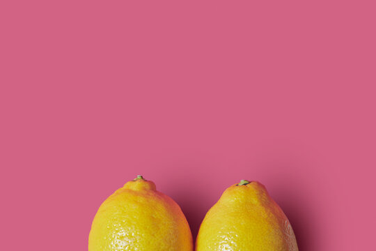 Two yellow lemons on pink background