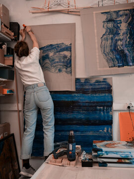 Redhead young woman attaching her works to the wall view from the back