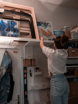 Female reaching up for tools in art studio