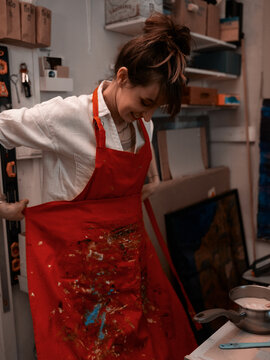 Business women in art studio tieding up a red apron smiling