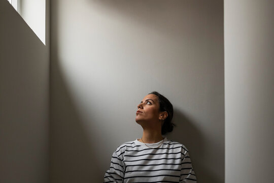 Young Woman Looking Out The Window Of Her House