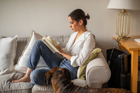 Caucasian young woman reading a book at home
