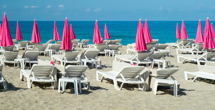 Bright pink parasols and sun loungers on a morning beach