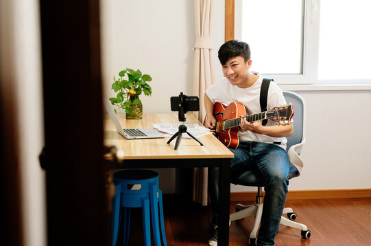 Young man with guitar live streaming his performance