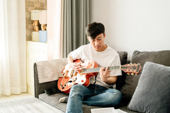 Young man playing guitar at home