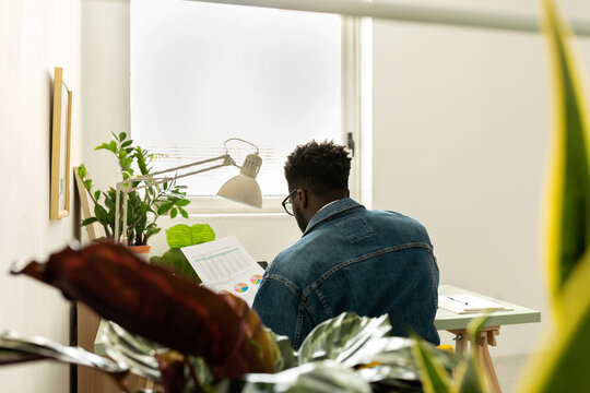 Black man working in office under window