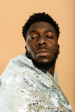 Black man posing with silver sequin cloak