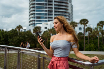 Woman using her mobile phone at the city park in Miami
