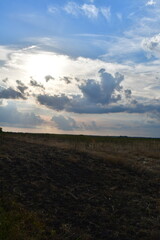 Sun in the Clouds Over a Rural Farm Field