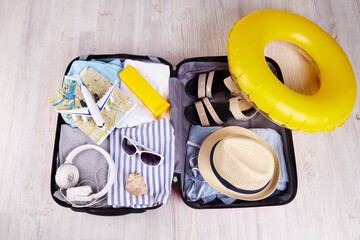 An open suitcase with things and accessories for a summer trip. Preparing for a trip to a seaside resort, packing luggage.